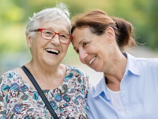 Lachende Seniorin mit einer Pflegefachfrau